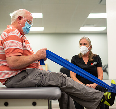 Patient stretching ankle with physical therapist supervising