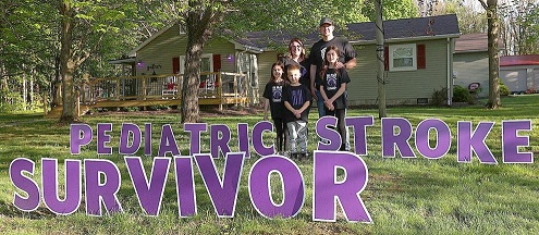 Hillis Family Stands Outside Home with Sign Reading: "Pediatric Stroke Survivor"